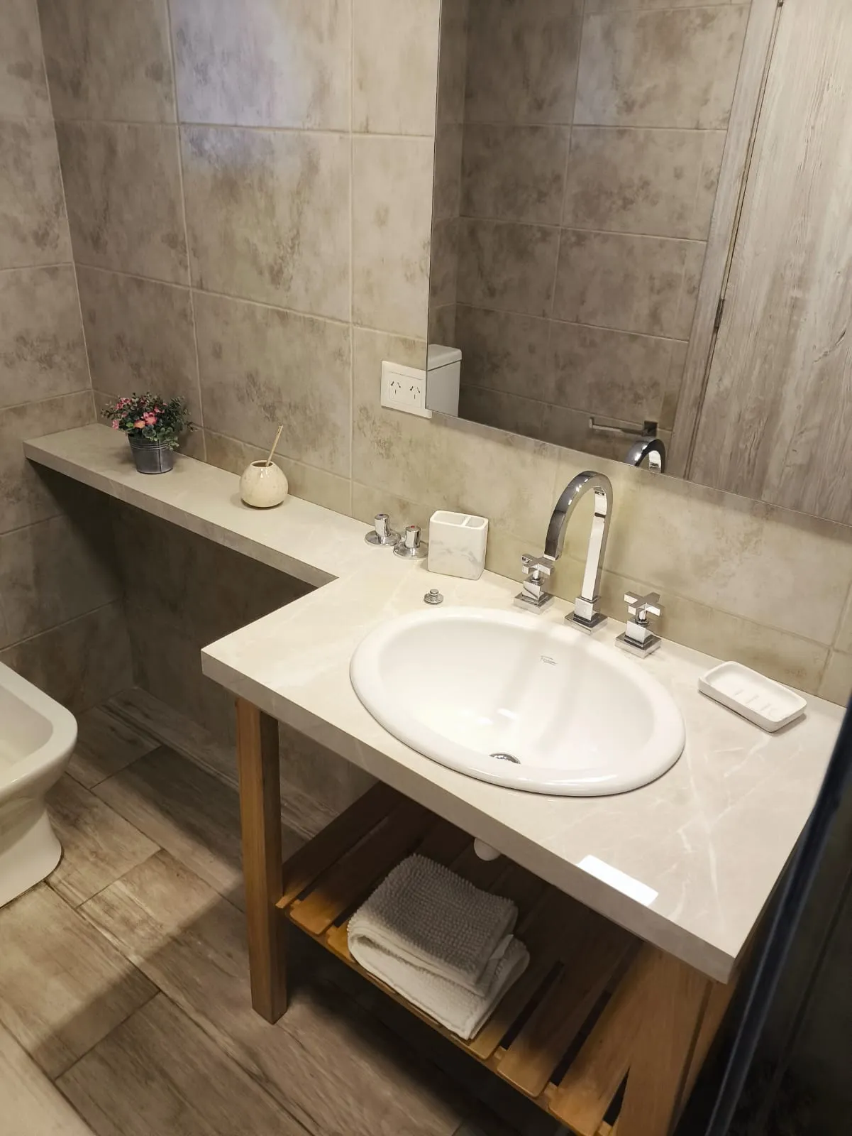 Baño con vanitory de madera y mesada de mármol