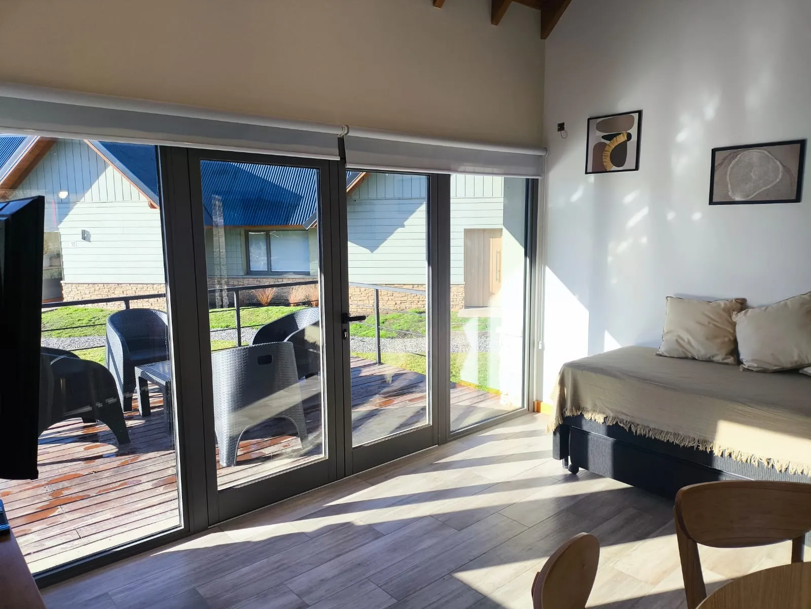 Living comedor con ventanales de piso a techo y salida al deck de madera